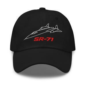 Op de afbeelding: Zwarte baseballpet met een witte geborduurde omtrek van een SR-71 Blackbird-vliegtuig en de tekst "SR-71" in rood.