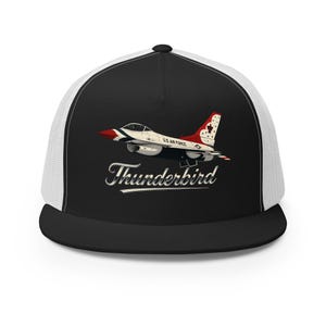 May include: Black and white trucker hat featuring a graphic of a red, white, and blue Thunderbird jet. The hat has a black brim and crown with a white mesh back. The text "Thunderbird" is written in a cursive font.