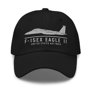 Peut inclure: Casquette de baseball noire avec un avion de chasse gris et le texte "F-15EX EAGLE II UNITED STATES AIR FORCE" en blanc. La casquette a une visière incurvée et un bouton sur le dessus.