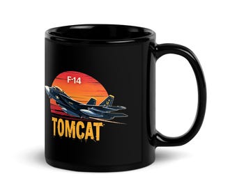 May include: Black ceramic mug with a graphic of an F-14 Tomcat fighter jet against a sunset. The mug features the text "F-14" and "TOMCAT" in a distressed font, evoking a vintage aesthetic.