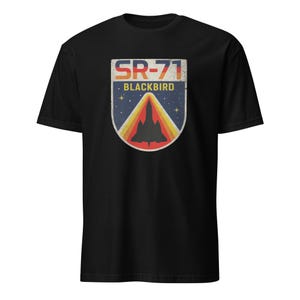 May include: Black t-shirt featuring a vintage-style graphic of the SR-71 Blackbird aircraft. The design includes the text "SR-71 BLACKBIRD" in a retro font, with a silhouette of the plane and a starry background. The graphic is in shades of red, orange, yellow, and blue.
