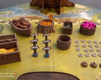 Puede incluir: Un juego de mesa con temática de bosque. Incluye un tablero de juego, un bote de madera, un cofre del tesoro con monedas, barriles, cestas y fichas. El tablero presenta el texto "Journey" y "Haven".