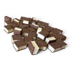 May include: A pile of chocolate-covered, book-shaped candies with white cream filling. The candies are dark brown and beige, scattered against a white background. The candies are arranged in a random pattern.