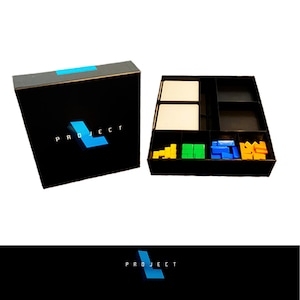 May include: A black board game box and game pieces. The box has the word "PROJECT" in white text with a blue "L" design. The game pieces are yellow, green, and blue. The game pieces are in a black tray.