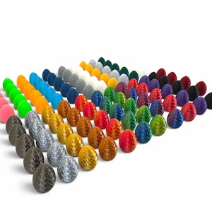 May include: A large collection of small, egg-shaped objects arranged in a grid. Each egg features a distinct, textured, scale-like pattern on its surface. The collection includes a wide variety of solid colours, including pink, green, orange, blue, grey, white, yellow, gold, brown, red, purple, and black.