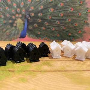 May include: A set of black and white birdhouses. The black birdhouses are made of a smooth, hard plastic. The white birdhouses are made of a smooth, hard plastic. The birdhouses are arranged in two rows on a wooden surface.