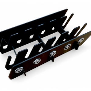 Puede incluir: Portacuchillos de metal negro con un dise&ntilde;o de varios niveles y m&uacute;ltiples ranuras para guardar cuchillos. El portacuchillos tiene un logotipo hexagonal decorativo en cada lado.