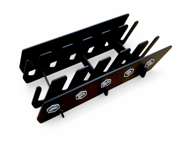 Puede incluir: Portacuchillos de metal negro con un dise&ntilde;o de varios niveles y m&uacute;ltiples ranuras para guardar cuchillos. El portacuchillos tiene un logotipo hexagonal decorativo en cada lado.