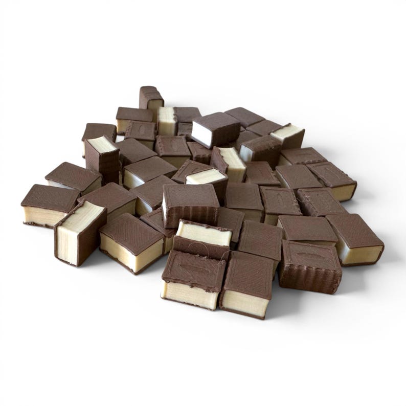 May include: A pile of ice cream sandwiches with a dark chocolate coating and vanilla ice cream filling. The sandwiches are rectangular and arranged in a random pattern against a white background. The chocolate has a slightly textured appearance.