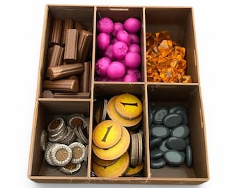 以下が含まれることがあります： 6つの区画に分かれた茶色の木製の箱。各区画には、木の棒、ピンクの星、オレンジ色の宝石、小さな木の円盤、1の数字が書かれた黄色の円盤、灰色の石など、さまざまなゲームの駒が入っています。