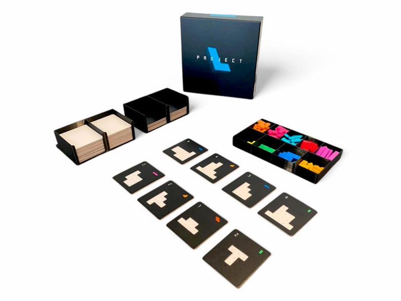May include: A board game set with a black box labelled "PROJECT" in white and blue. The set includes black card holders, game cards, and colourful plastic game pieces. The cards have white geometric shapes.