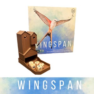 May include: A board game box and wooden game piece holder. The box features a bird with outstretched wings. The game piece holder is brown and shaped like a birdhouse. Dice with bird illustrations are in the tray.