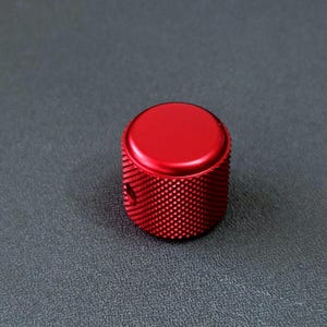 Peut inclure: Un bouton en métal rouge avec une surface texturée. Le bouton est rond et a un dessus lisse.