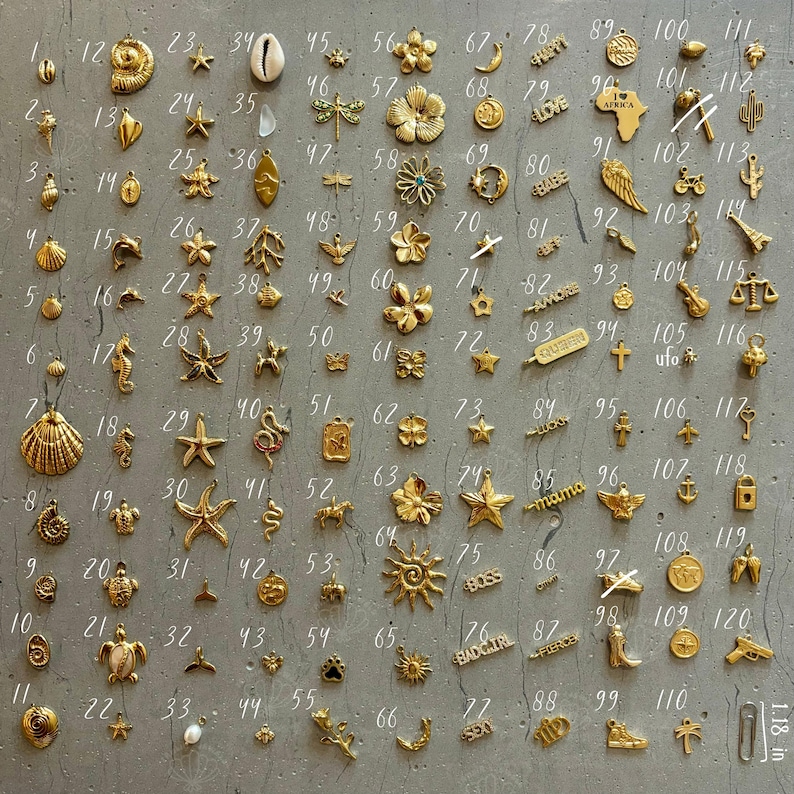 K&ouml;nnte beinhalten: Ein Raster mit 120 goldfarbenen Charms, jeder mit einem anderen Design. Die Charms sind in 12 Reihen mit jeweils 10 Charms angeordnet. Die Charms umfassen eine Vielzahl von Formen, darunter Sterne, Herzen, Muscheln, Tiere und W&ouml;rter. Die Charms sind alle etwa 1,27 cm gro&szlig;.