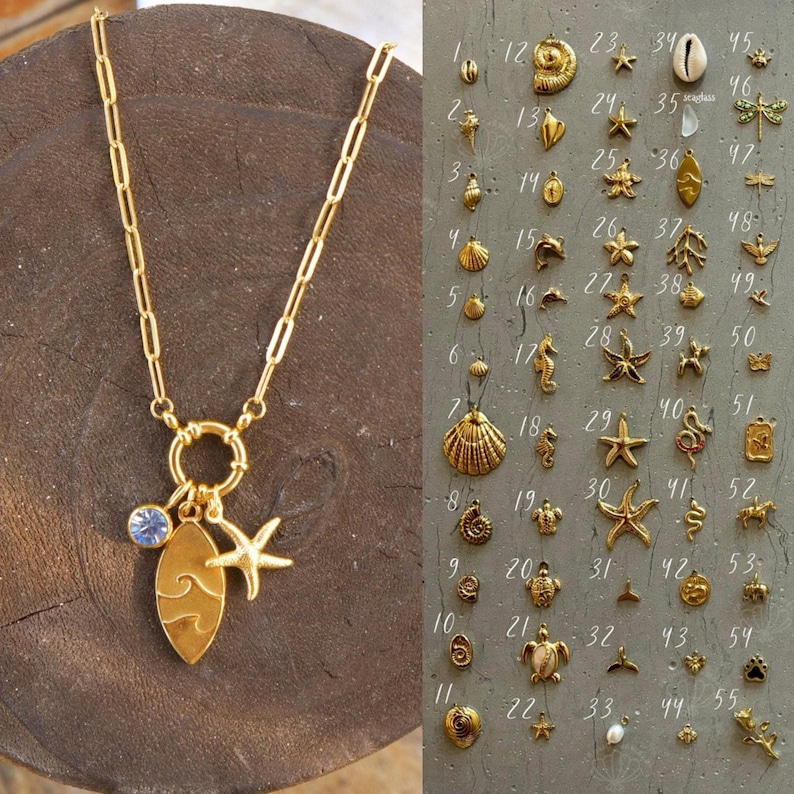 K&ouml;nnte beinhalten: Eine goldene Kettenkette mit einem Anh&auml;ngerhalter, der ein Surfbrett, einen Seestern und einen klaren Kristall zeigt. Der Anh&auml;ngerhalter ist an einem Ring befestigt. Die Kette wird auf einer Holzoberfl&auml;che pr&auml;sentiert. Das Bild zeigt auch ein Raster mit 55 verschiedenen goldenen Anh&auml;ngern, darunter Muscheln, Seesterne, Seepferdchen und andere nautische Designs.
