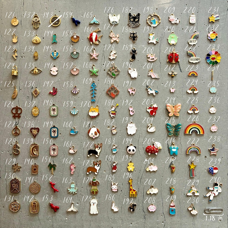 K&ouml;nnte beinhalten: Eine Sammlung von 100 Emaille-Anh&auml;ngern in verschiedenen Farben und Designs. Die Anh&auml;nger sind in Reihen auf einer grauen Oberfl&auml;che angeordnet. Die Anh&auml;nger umfassen Tiere, Pflanzen, Lebensmittel und andere Gegenst&auml;nde. Die Anh&auml;nger sind etwa 3 cm gro&szlig;.