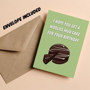 May include: A greeting card with a green background and the text "I HOPE YOU GET A WOOLIES MUD CAKE FOR YOUR BIRTHDAY". The card features an illustration of a chocolate mud cake. A brown envelope is included.