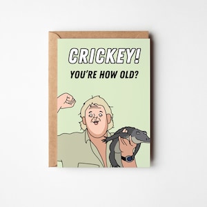 May include: A green and white birthday card with a cartoon image of a man holding a crocodile. The card says "CRICKEY! YOU'RE HOW OLD?"