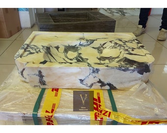May include: A rectangular marble sink with a cream and black veined pattern. The sink has a built-in basin and is packaged on a wooden crate. The logo "V Design Marble Store" is visible on the packaging.