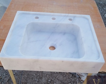 Peut inclure: Évier de salle de bain en marbre blanc de forme rectangulaire avec un trou de vidange unique. L'évier comporte trois trous pour robinets.