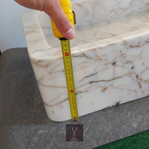 May include: A white marble sink with brown veining. The sink is 20 inches wide.