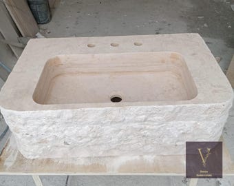 Pia de parede externa em travertino com acabamento rústico e furos espaçados para torneira.