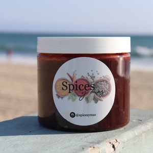 Puede incluir: Un tarro de vidrio con tapa blanca lleno de salsa roja. El tarro tiene una etiqueta blanca con el texto "Spices y mas" y un nombre de usuario de Instagram "@spicesymas".