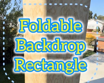 May include: A large, rectangular, foldable backdrop made of light-colored wood. The text "Foldable Backdrop Rectangle" is displayed in bright yellow and blue. The backdrop is standing upright on a concrete surface, with a blue sky in the background.