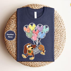 a t - shirt with a cartoon dog holding a bunch of balloons