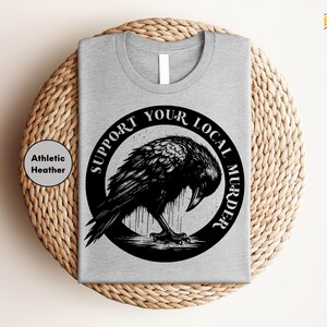 a grey t - shirt with a black bird on it