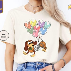 a woman wearing a t - shirt with a dog holding a bunch of balloons