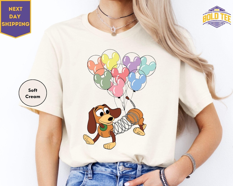 a woman wearing a t - shirt with a dog holding a bunch of balloons