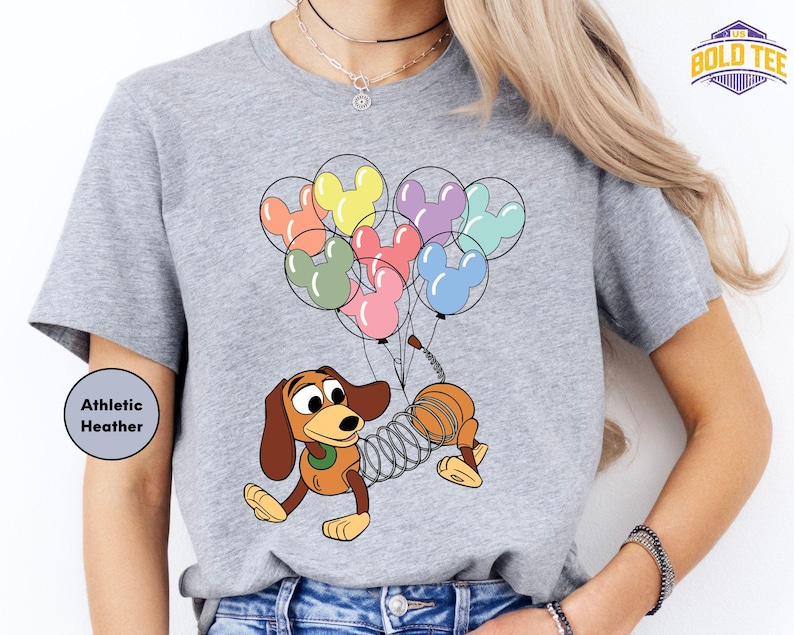 a woman wearing a shirt with a cartoon dog holding a bunch of balloons