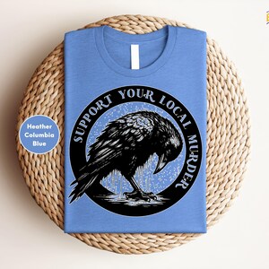 a blue t - shirt with a black bird on it
