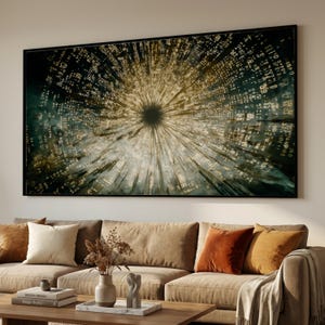 May include: Large framed abstract art print. The artwork features a central dark circle with radiating lines and a matrix of light-coloured text and symbols, set against a dark background. The print is displayed above a beige sofa with decorative cushions.