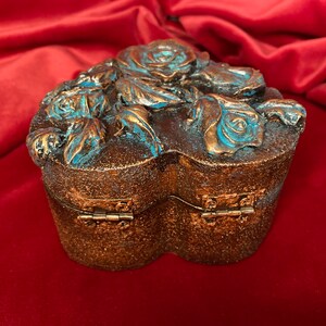 May include: A heart-shaped wooden box with a hinged lid, decorated with blue and gold roses. The box is perfect for storing small treasures or jewelry.