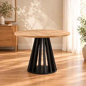 Puede incluir: Una mesa de comedor redonda con un tablero de madera de color marrón claro con veteado y una base de pedestal negra. La base consta de múltiples listones verticales dispuestos en una formación circular y cónica sobre una placa base negra.