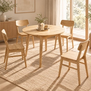 Op de afbeelding: Een ronde eettafel van lichtgekleurd hout met vier bijpassende houten stoelen eromheen. De tafel heeft een glad, rond blad dat rust op vier taps toelopende poten, en elke stoel is voorzien van een gebogen rugleuning en vier rechte poten.