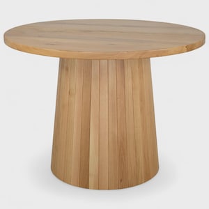 Könnte beinhalten: Ein runder Holztisch mit hellbraunem Finish. Die Tischplatte ist kreisförmig, und das Gestell hat eine ausgestellte, zylindrische Form, die aus vertikalen Holzplanken besteht. Der Tisch hat eine natürliche Holzfarbe.