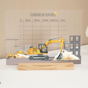 Könnte beinhalten: Eine transparente Stundenplantafel aus Acryl mit einem Baustellenthema. Die Tafel zeigt einen gelben Bagger, einen Betonmischer und andere Baufahrzeuge. Der Text "Stundenplan von Nico" steht oben, darunter ein Wochenplanraster. Sie wird von einem Holzsockel getragen.
