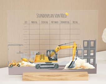 Peut inclure: Un tableau de planification en acrylique transparent sur le thème de la construction. Le tableau présente une excavatrice jaune, une bétonnière et d'autres véhicules de chantier. Le texte "Stundenplan von Nico" est en haut, avec une grille d'horaire hebdomadaire en dessous. Il est soutenu par une base en bois.