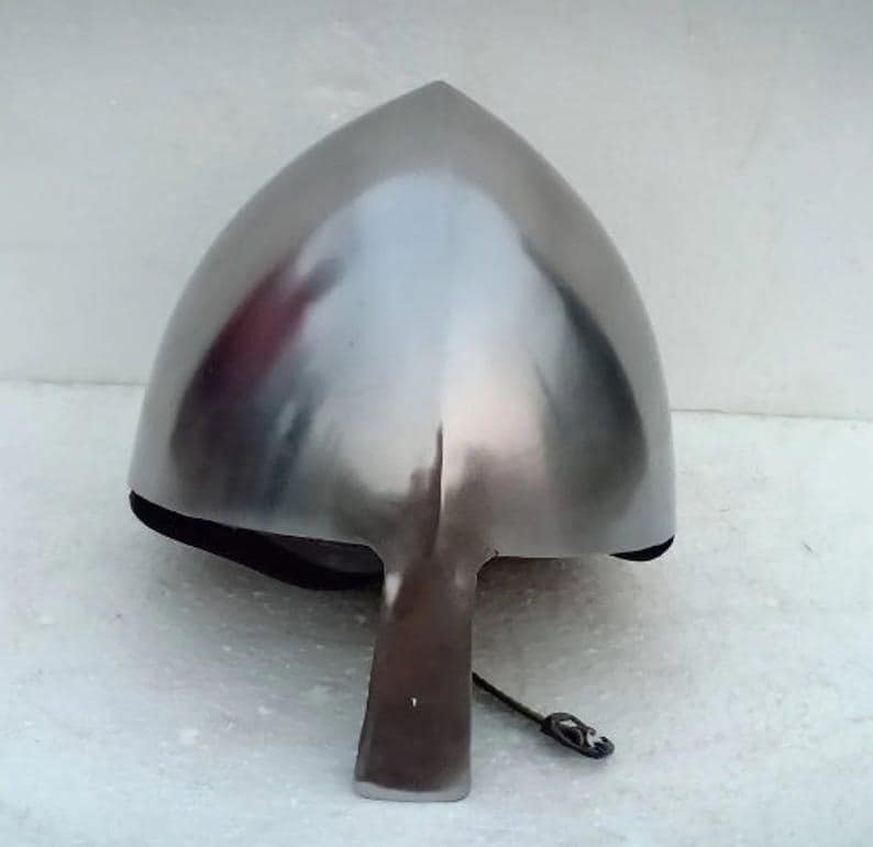 May include: A polished, silver-colored medieval helmet with a pointed top and a face guard. The helmet is made of metal and has a smooth, reflective surface. The helmet is designed to protect the head and face.