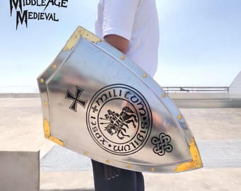 May include: A silver-colored medieval shield with gold-colored trim and rivets. The shield features a black cross and a circular emblem with a knight on horseback. The text "MIDDLE AGE MEDIEVAL" is in the upper left corner.
