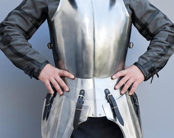 May include: A polished steel breastplate with attached waist and hip protection. The armor features black leather straps and buckles for fastening. The person is wearing a gray jacket with black accents.