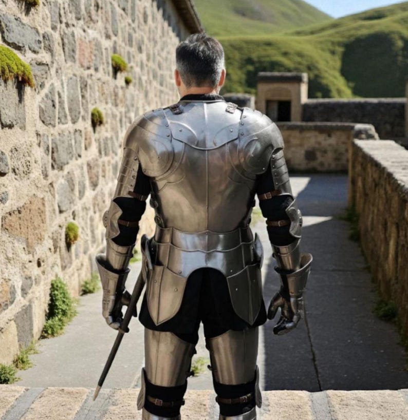 May include: A suit of polished steel plate armor worn from the back, featuring a breastplate, pauldrons, gauntlets, and greaves secured with brown leather straps over a black garment, with a long thin sword held in the right hand.