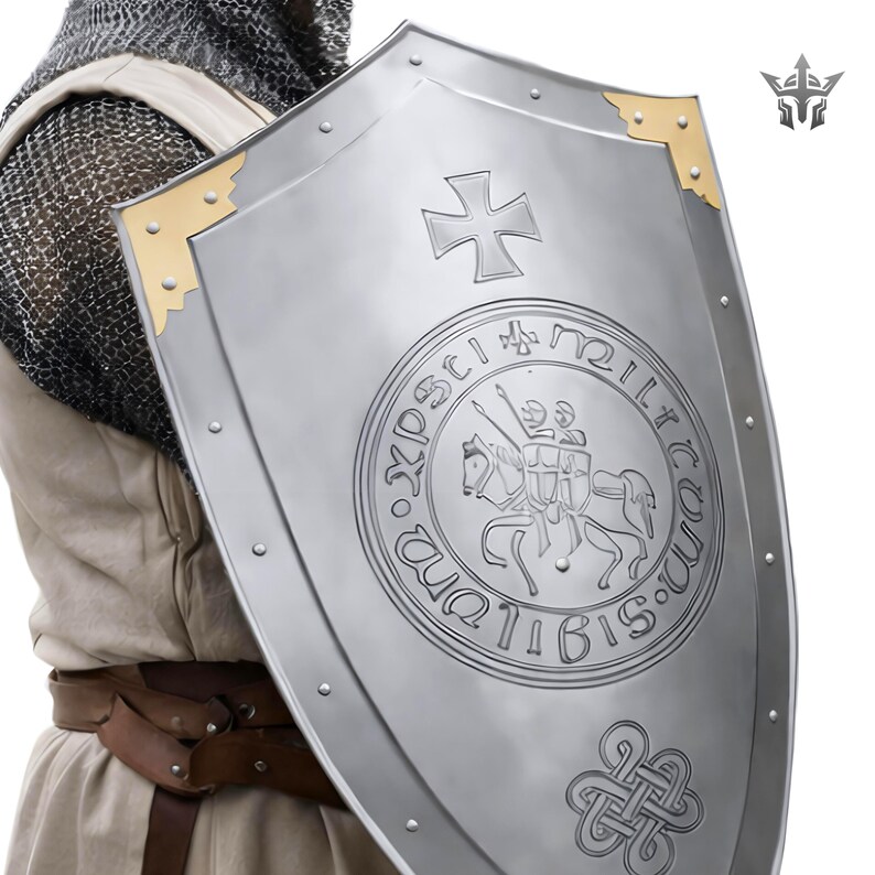 May include: A silver-colored medieval shield with a cross emblem and a circular design featuring two knights on horseback. The shield has gold-colored corner accents and rivets along the edges.