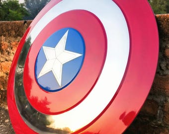Puede incluir: Un escudo rojo, blanco y azul con un emblema de estrella. El escudo tiene un acabado brillante y un diseño circular. El centro presenta un círculo azul con una estrella blanca. El escudo es un accesorio o artículo de colección.