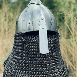 May include: A medieval-style helmet with a pointed top and a metal visor. The helmet is made of shiny, silver-colored metal and is riveted. A chainmail coif extends down to the shoulders.
