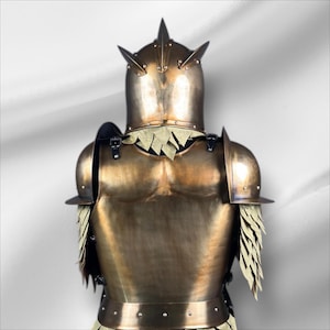 Op de afbeelding: Een bronskleurig harnas, van achteren bekeken, met een helm met drie opvallende punten. Het harnas omvat schouderbeschermers en decoratieve elementen die op veren lijken. Het algehele ontwerp suggereert een middeleeuws of fantasiethema.