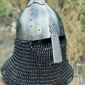 May include: A medieval-style helmet with a pointed top and riveted construction. The helmet is made of shiny metal and features a chainmail neck guard. The design is reminiscent of historical armor.